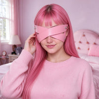 Pink faux-leather cross-strap eye mask worn close-up on a model, the whole X in view