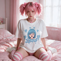 Model sitting with knees drawn up on the bed, the anime print visible across the front of the tee
